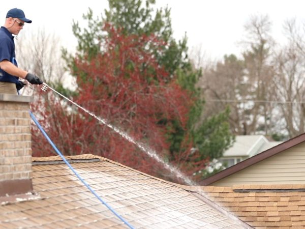 A man is power washing the roof