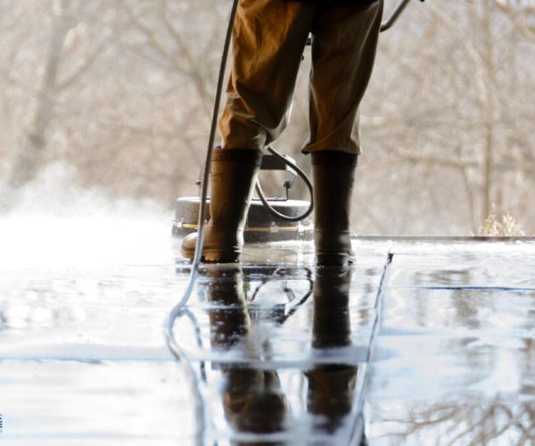 A man is pressure washing the concrete floor